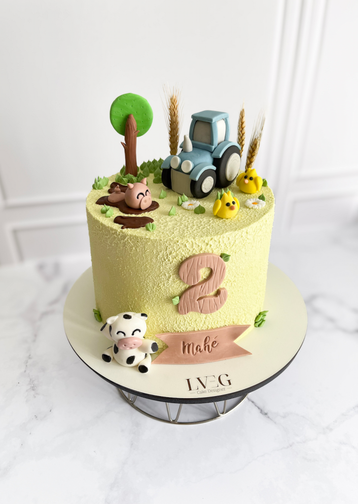 Cake Design sur le thème de la ferme vert décoré d'animaux, de végétation et d'un tracteur en pâte à sucre