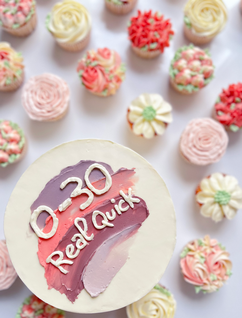 Cake Design décoré d'une palette de couleur rose et une inscription "0-30 Real Quick" accompagné d'une vingtaine de Cupcakes pochés au thème floral