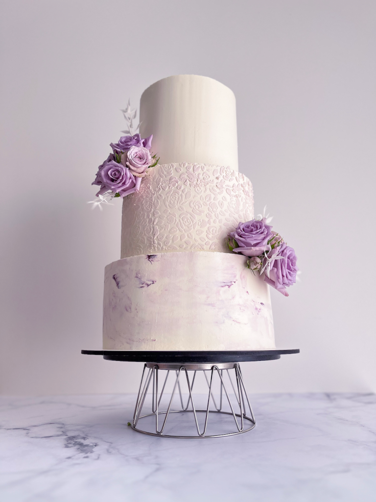 Pièce montée avec base en effet marbre violet, premier étage avec pochoir floral et deuxième étage élégant. Décoré en fleurs violettes