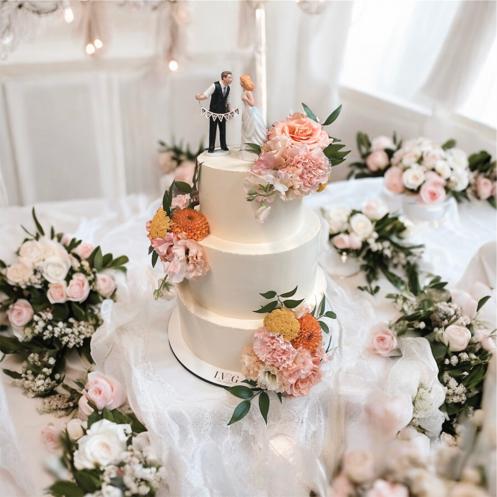 Wedding Cake sur trois étages blanc décoré de fleurs orangées et d'une figurine